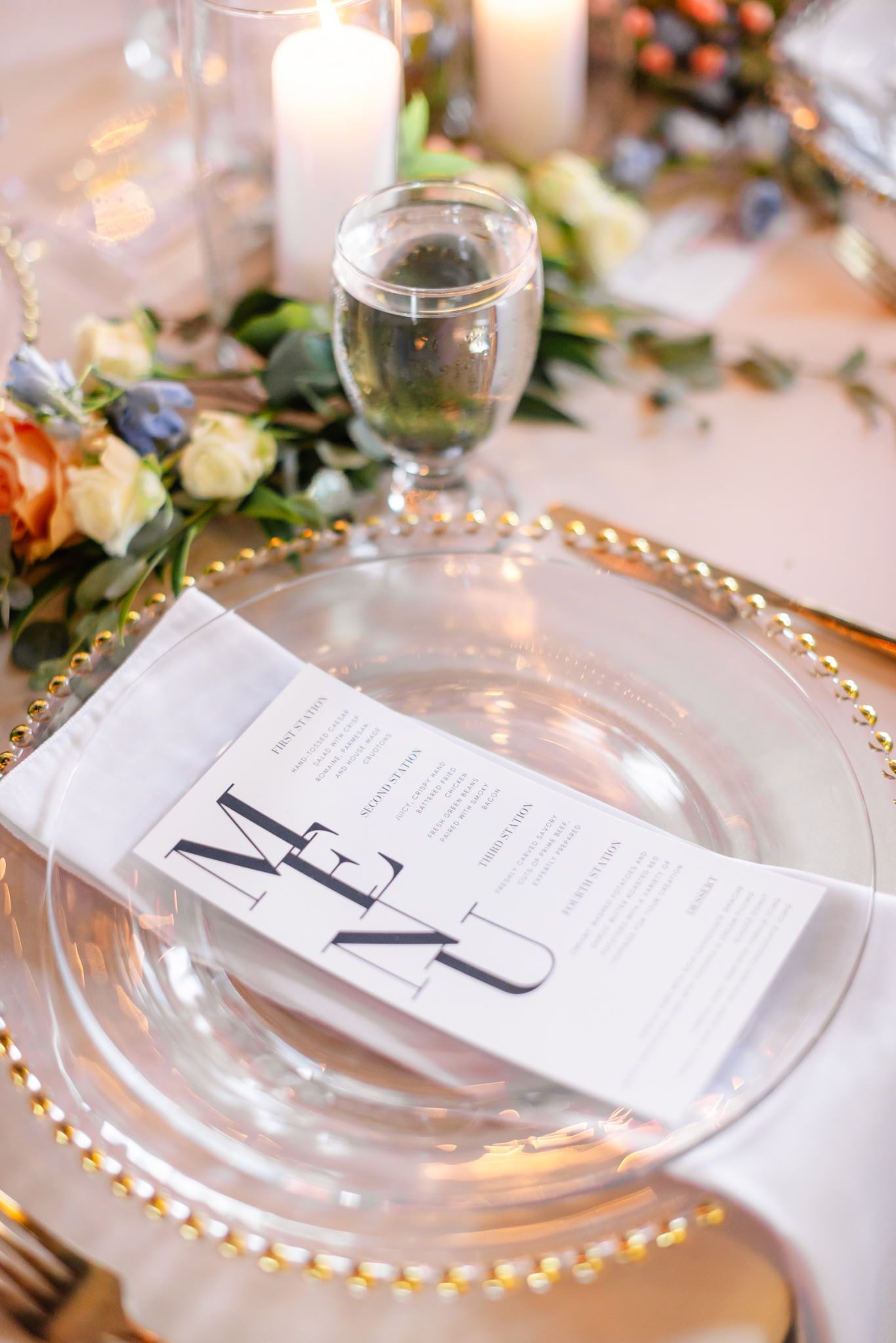 A place setting for a wedding reception with a menu on a plate.