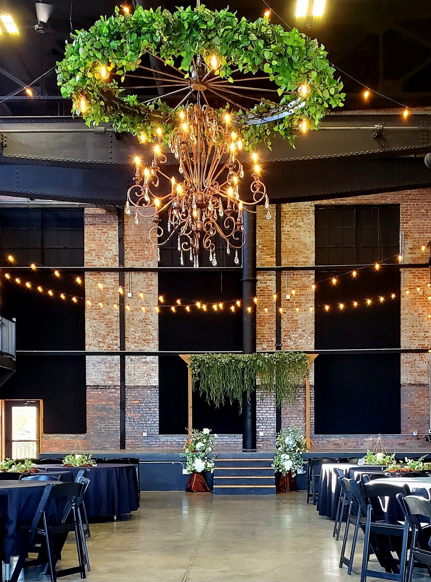 A large room with tables and chairs and a chandelier hanging from the ceiling