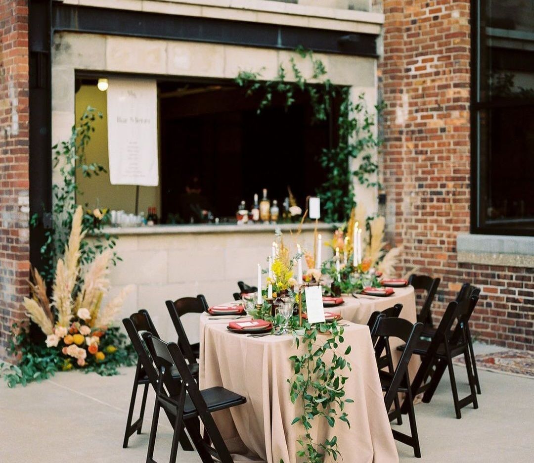 A table and chairs are set up in front of a brick building.