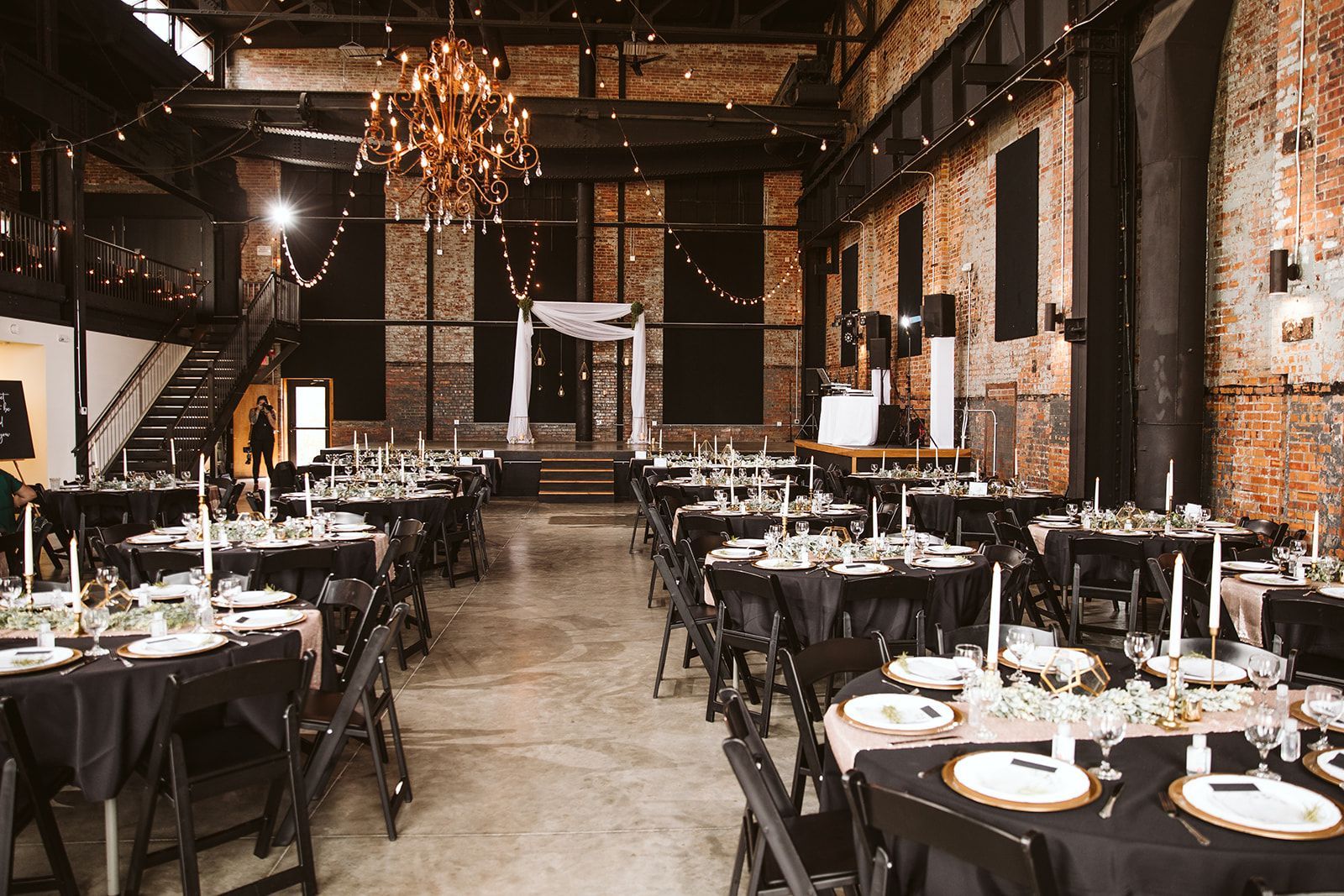 A large room filled with tables and chairs set up for a wedding reception.