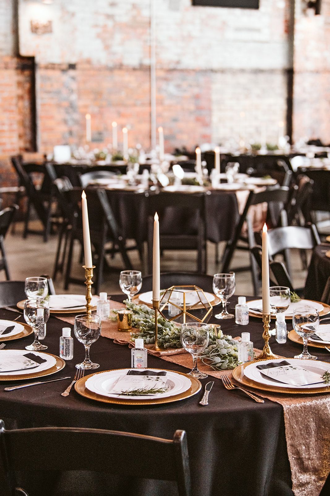 A table set for a wedding reception with plates , candles and glasses.