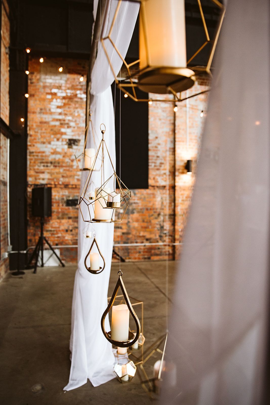 A room with candles hanging from the ceiling and a brick wall.