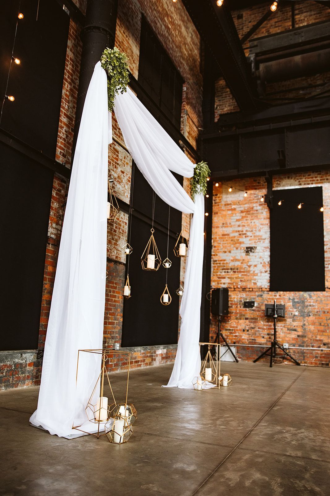 A large room with a white arch and candles hanging from the ceiling.