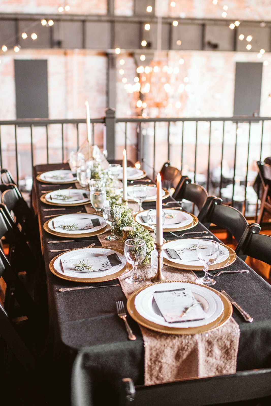 A long table with plates and candles on it is set for a wedding reception.