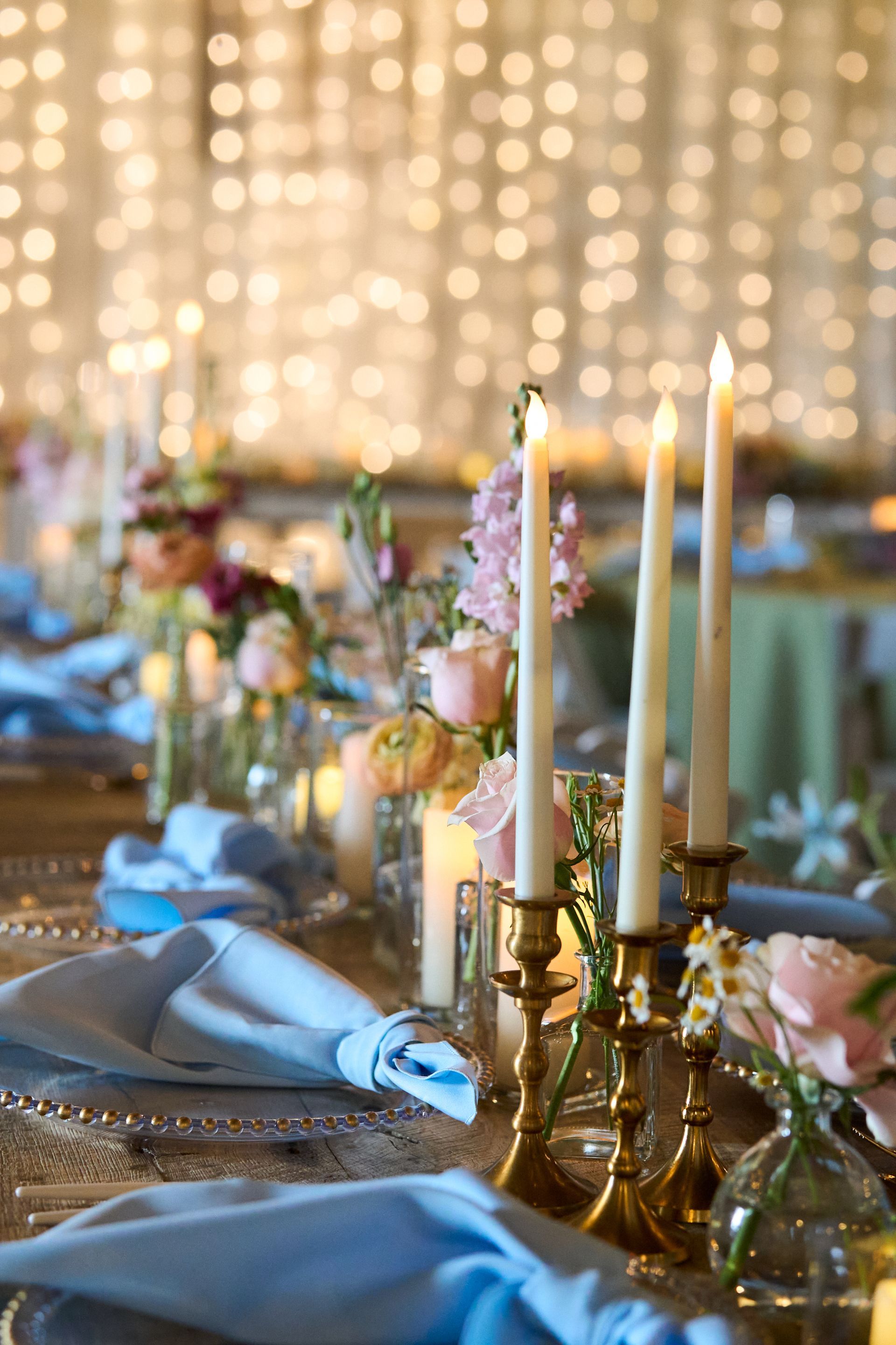 A table set for a wedding reception with candles and flowers on it.
