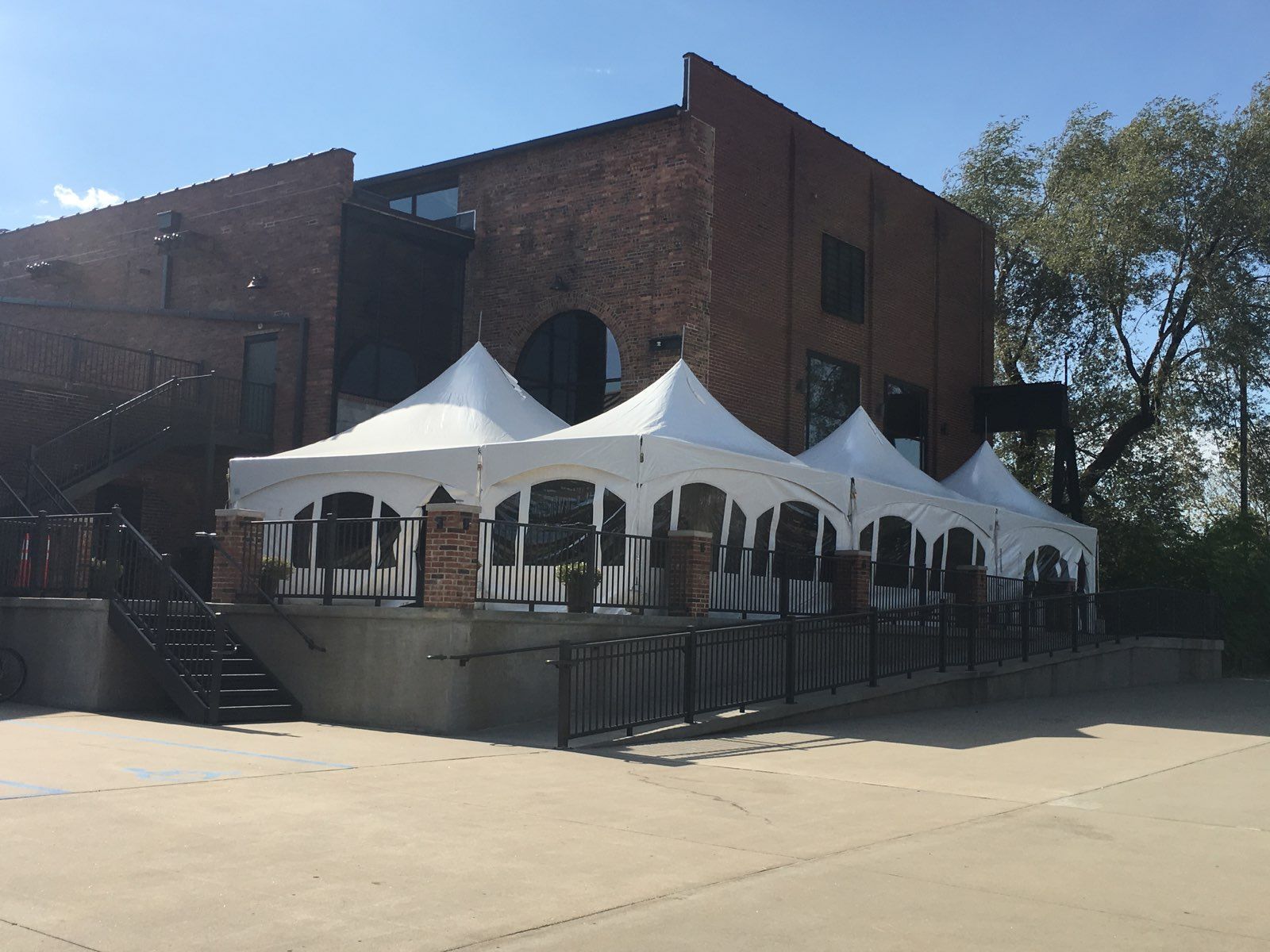 A row of white tents are sitting in front of a brick building.