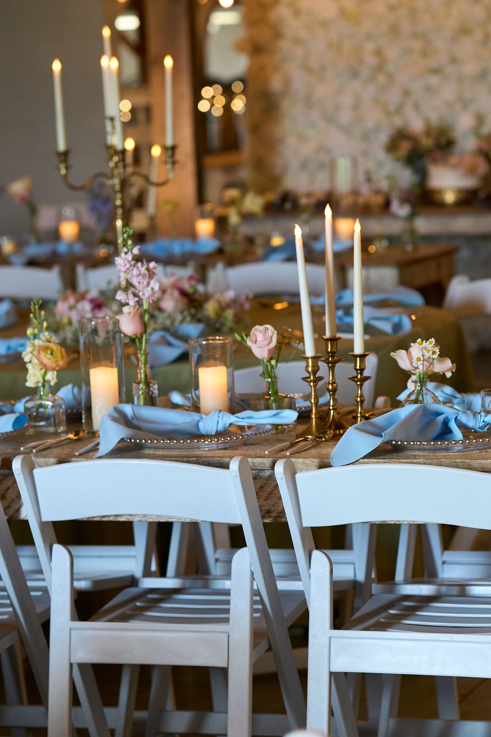 A table set for a wedding reception with candles and flowers on it.