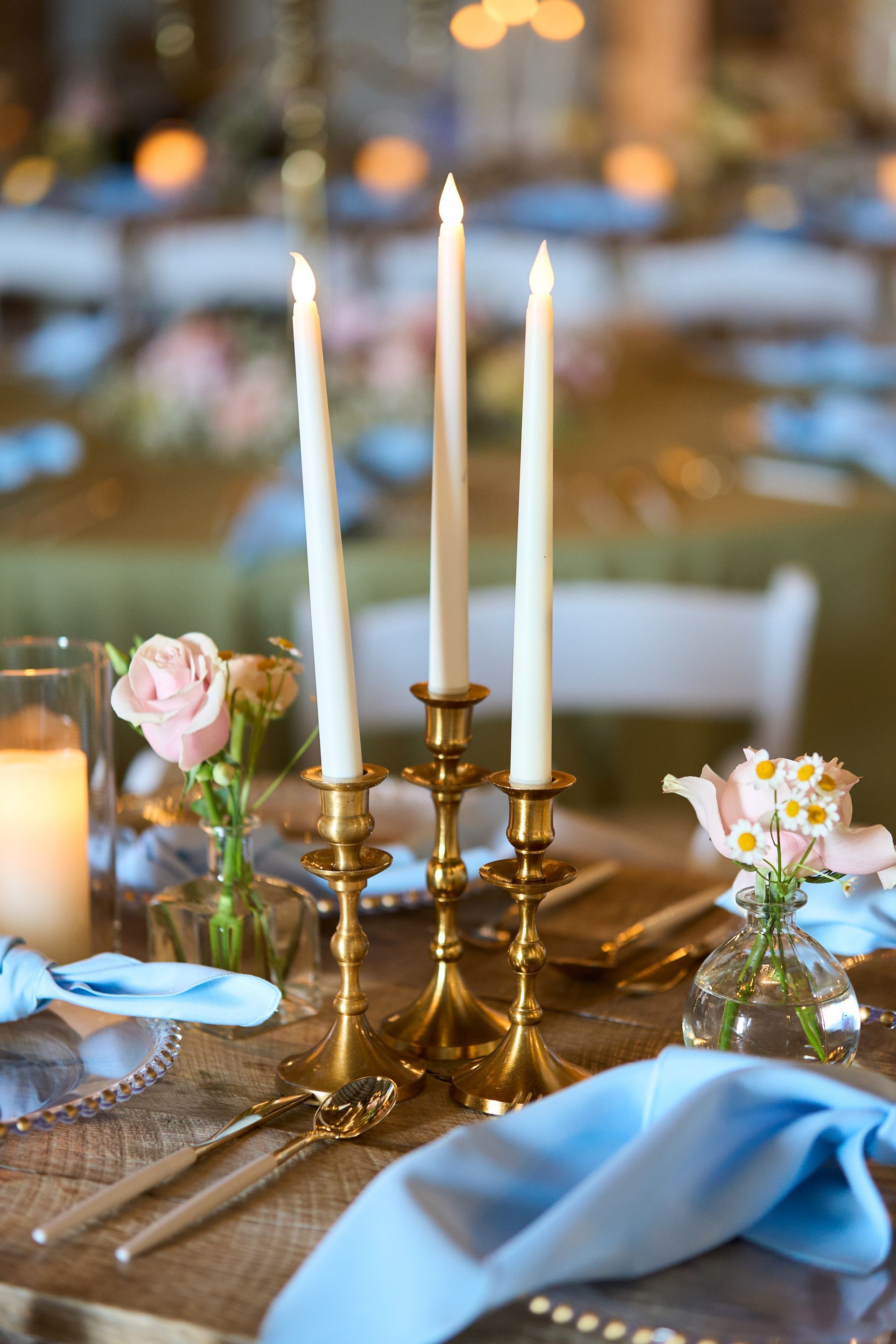 A table set for a wedding reception with candles and flowers on it.