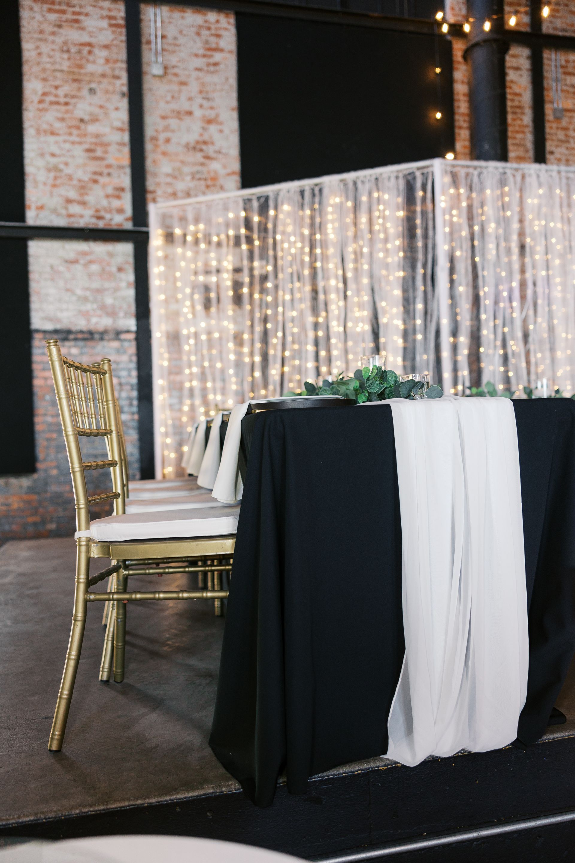 A table with a black table cloth and a white table runner.