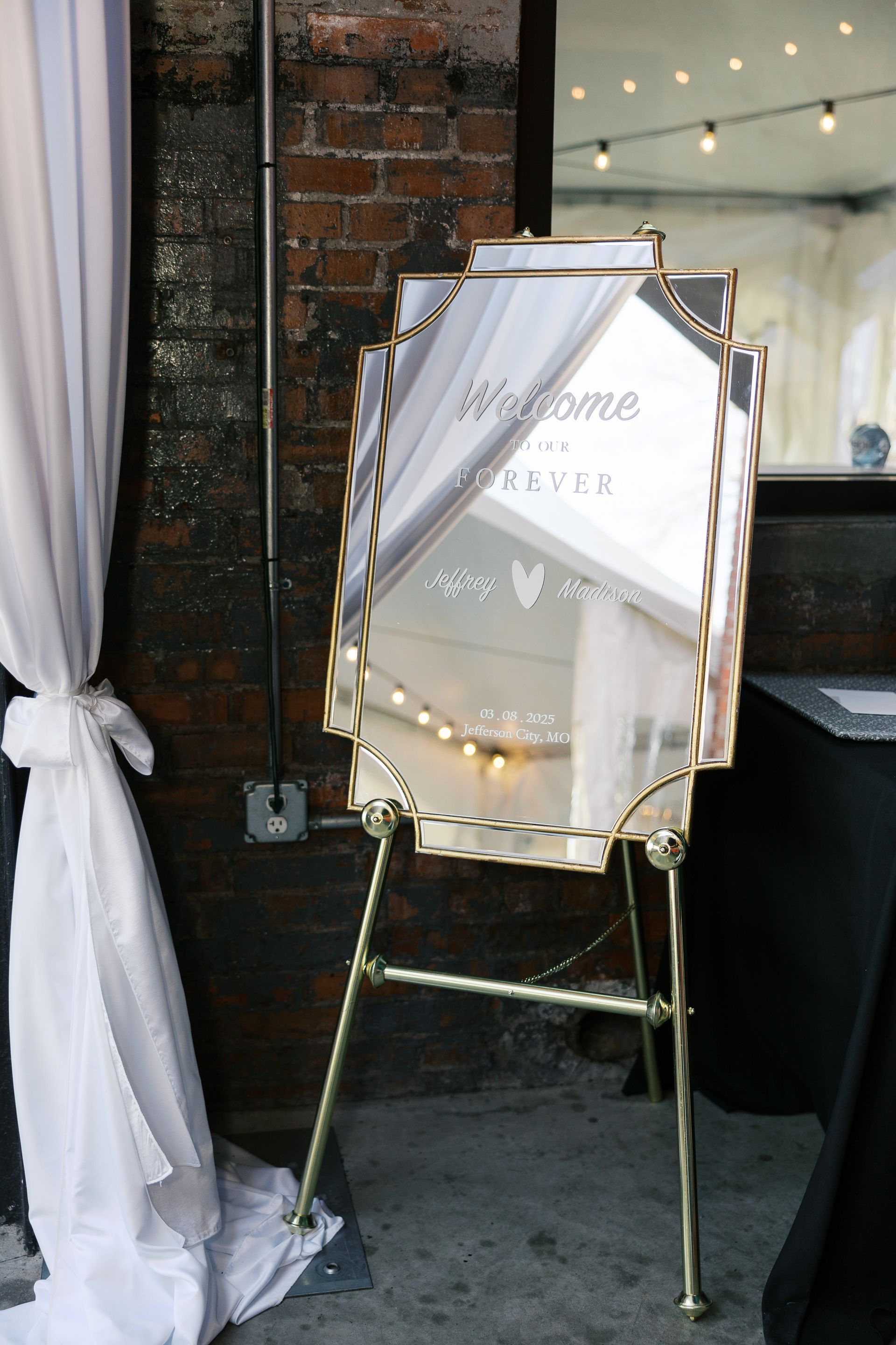 A large mirror is sitting on an easel in front of a brick wall.