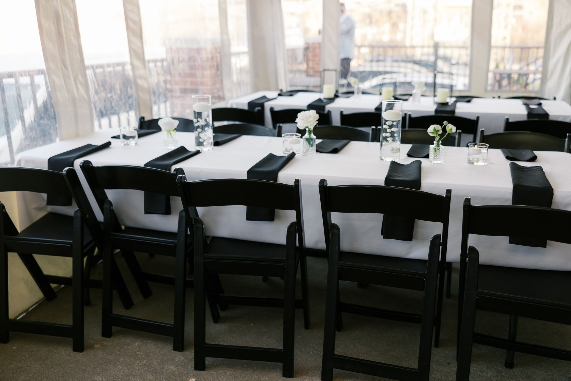 A long table with black chairs and white tables cloths
