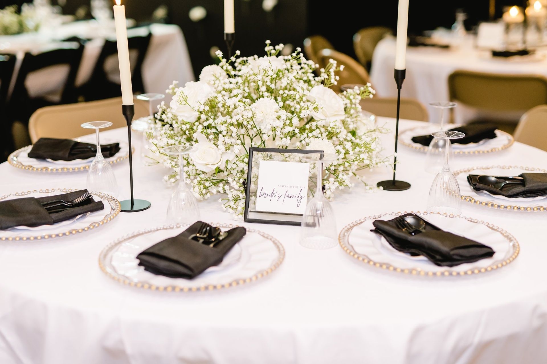 A table set for a wedding reception with plates , napkins , candles and a centerpiece of baby 's breath.