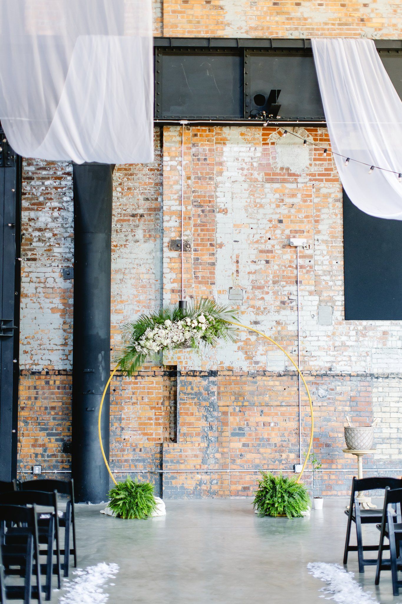 A wedding ceremony is taking place in front of a brick wall.