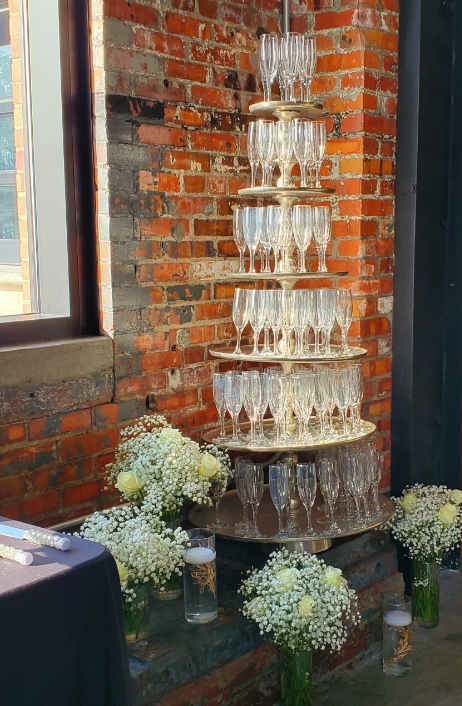 A tower of champagne glasses against a brick wall