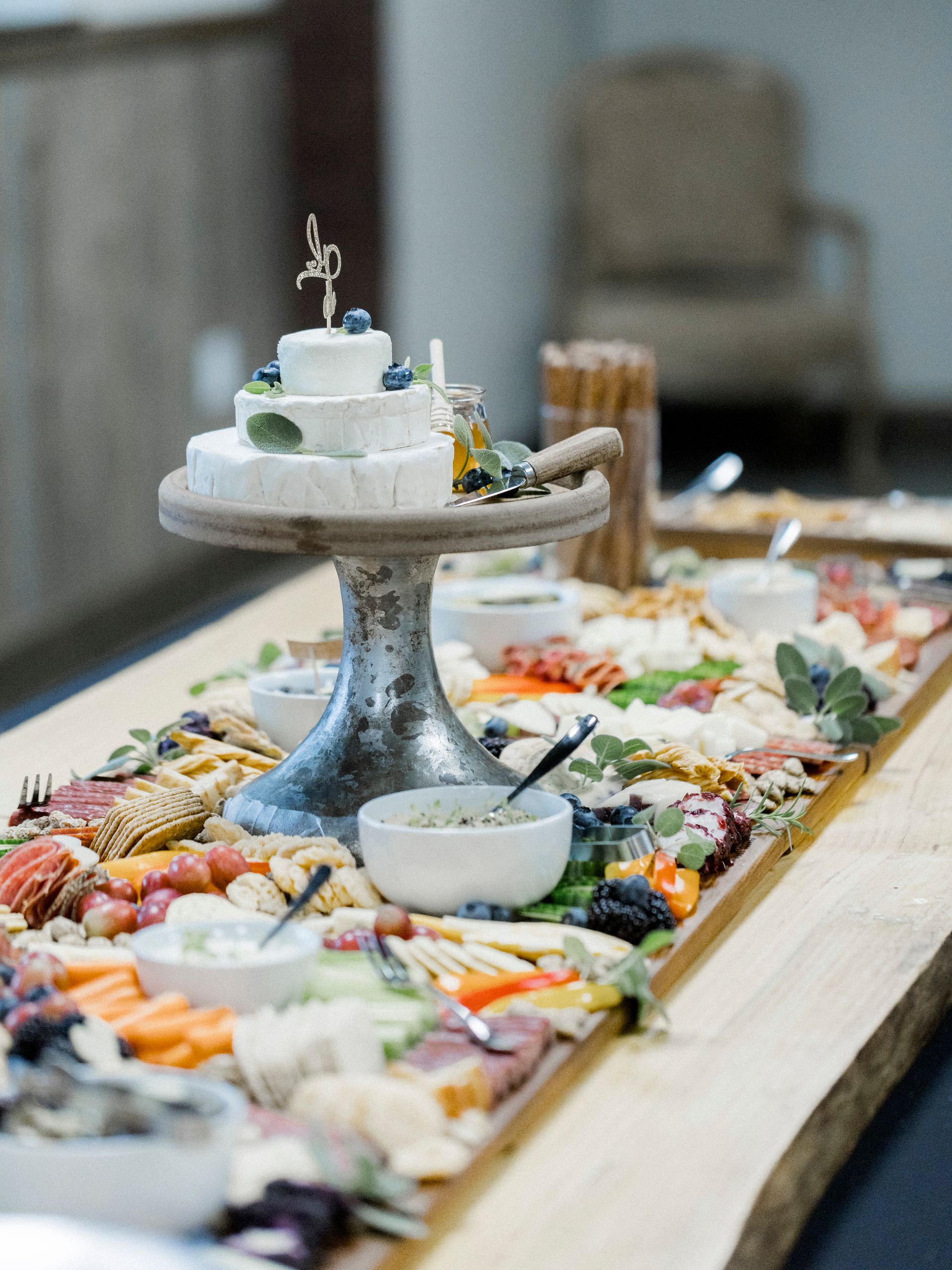 A long wooden table topped with lots of food and a cake on top.