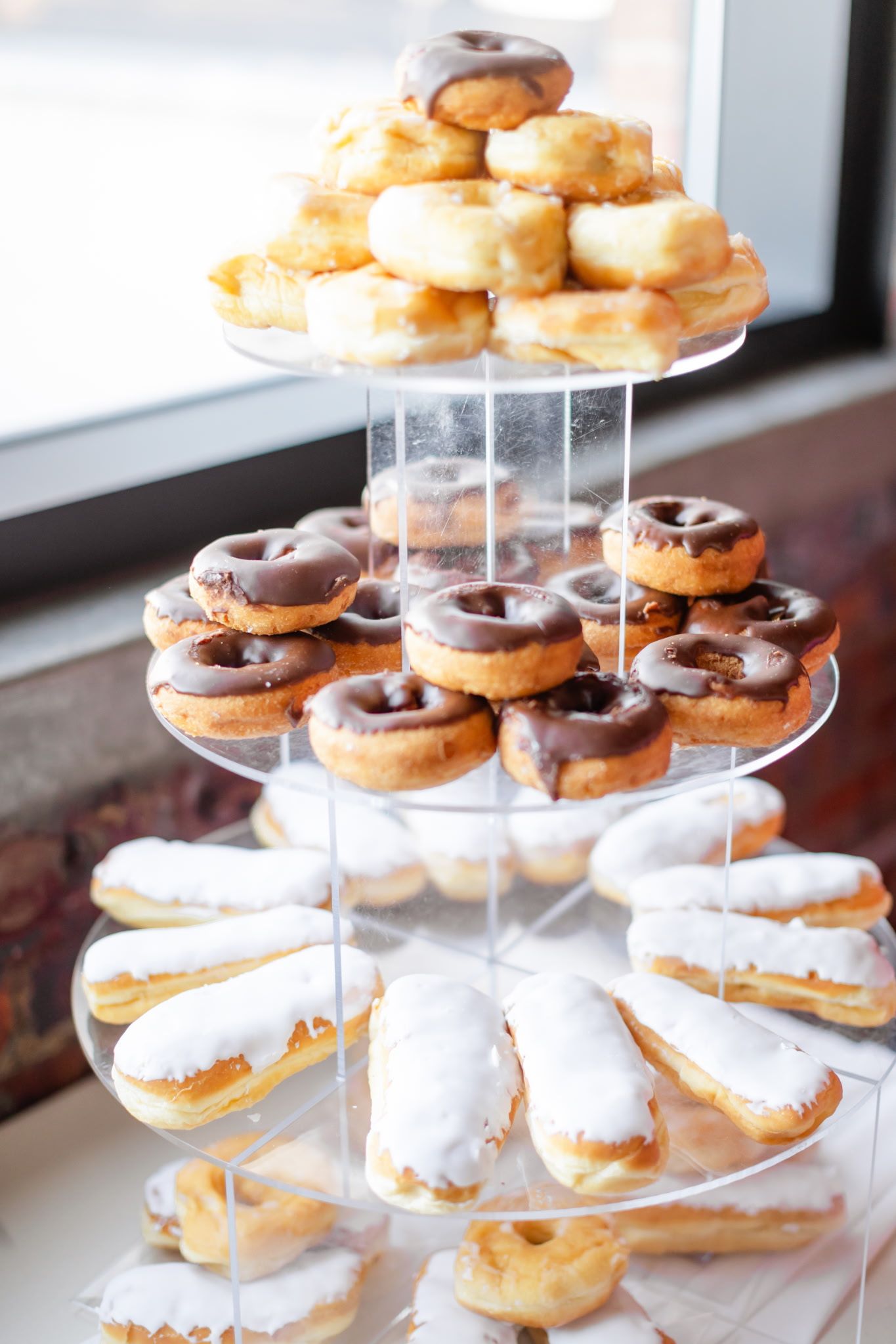 A tower of donuts with chocolate and white frosting on a table.
