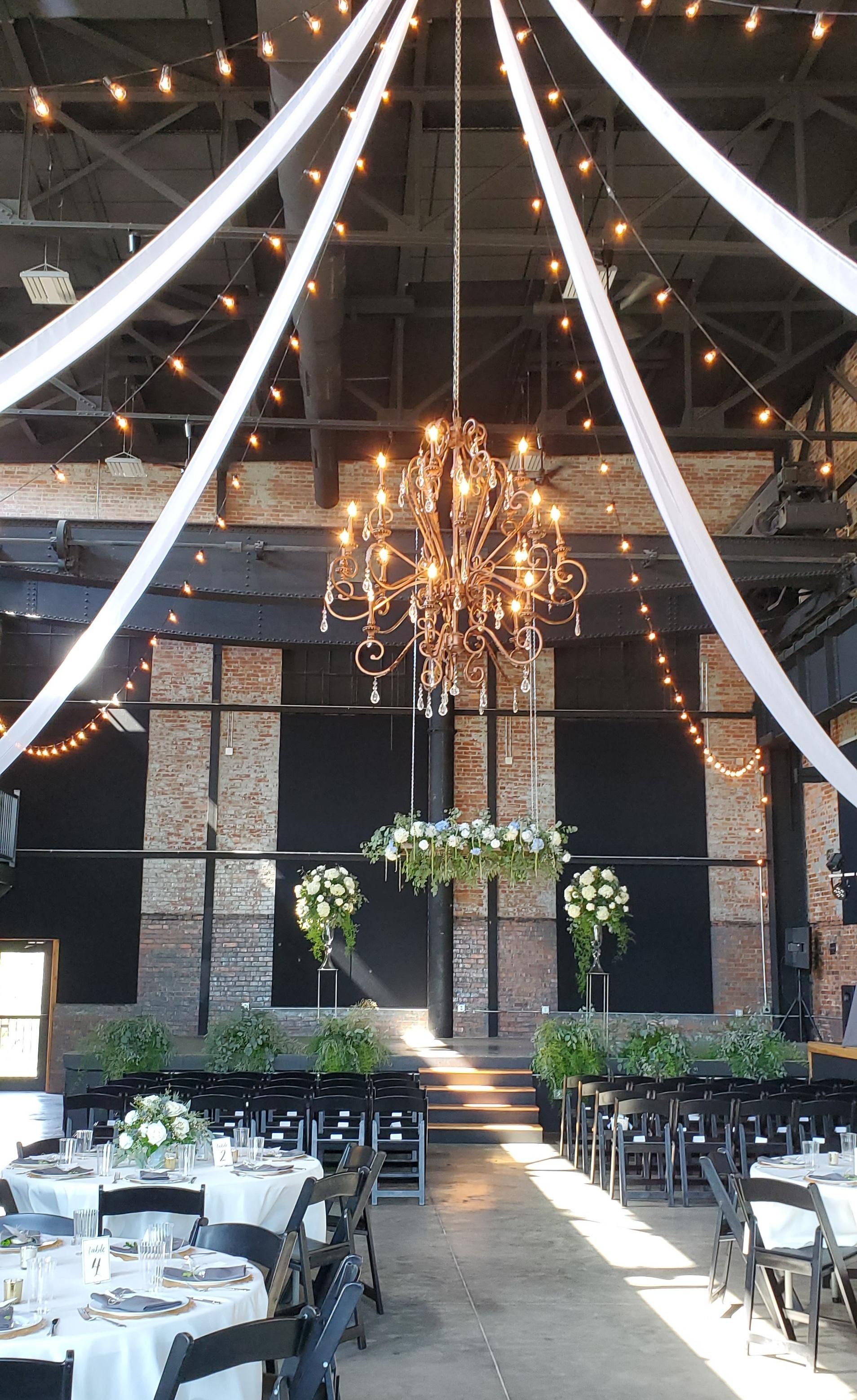 A large room with tables and chairs and a chandelier hanging from the ceiling.