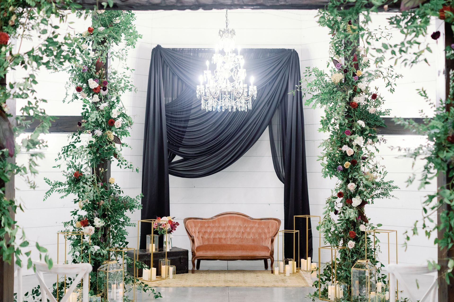 There is a couch in the middle of a room with flowers and candles.