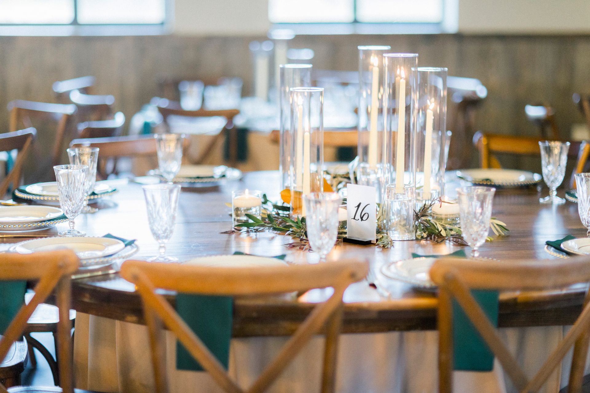 A table set for a wedding reception with candles and glasses on it.