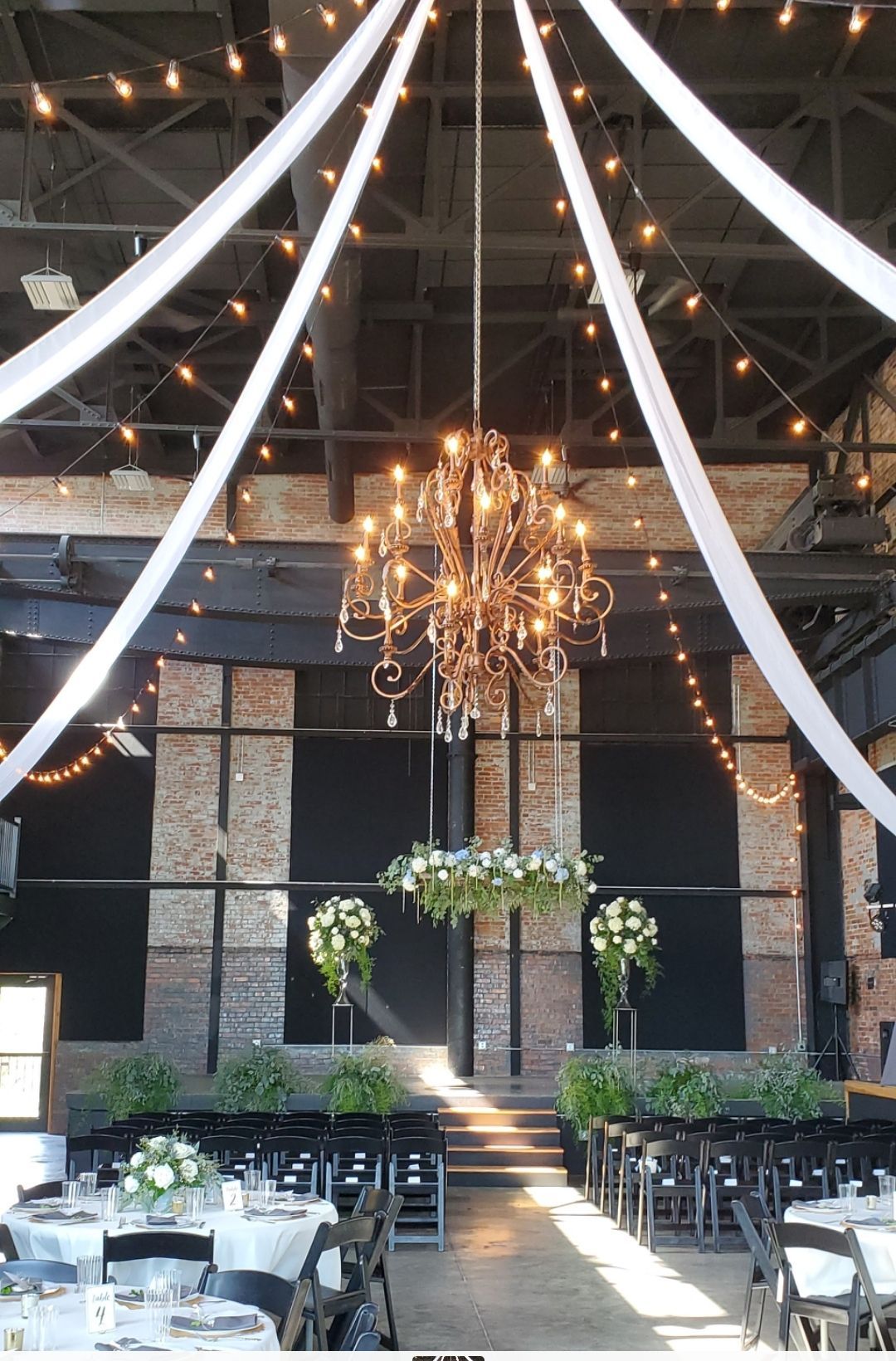 A large room with tables and chairs and a chandelier hanging from the ceiling