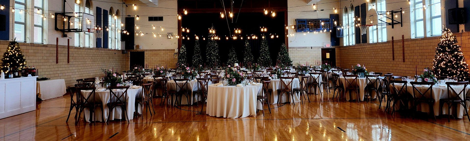 A large room filled with tables and chairs and christmas trees.