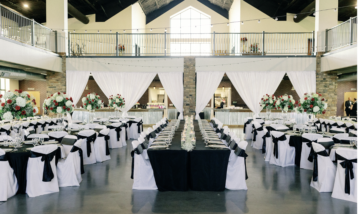 A large room with tables and chairs set up for a wedding reception.