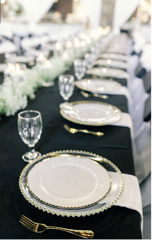 A long table with plates , glasses , forks and spoons on it.