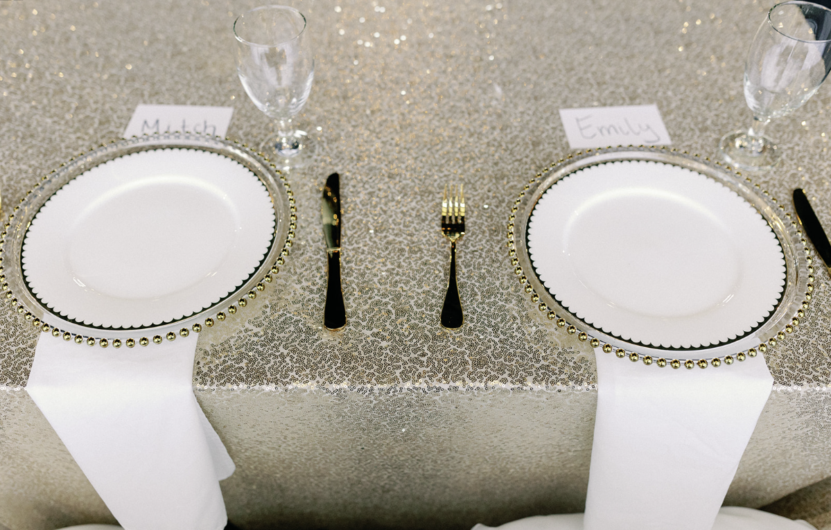 A table with plates , silverware , glasses and a name tag on it.