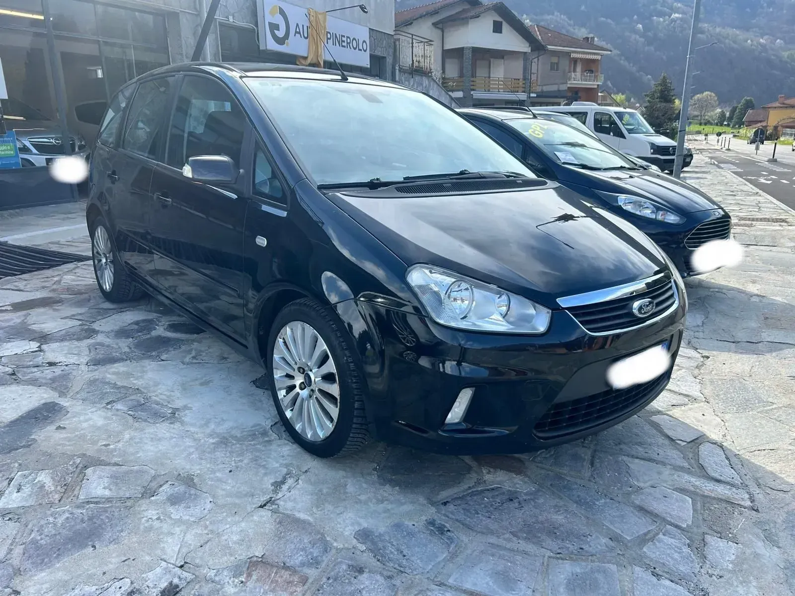 Furgone compatto nero parcheggiato su una strada innevata di fronte alle case