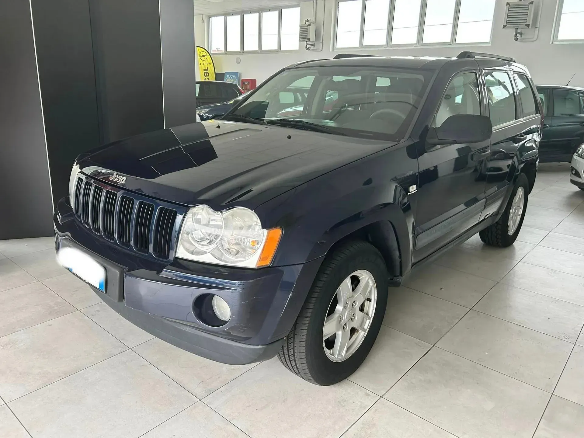SUV blu scuro parcheggiato all'interno di uno showroom luminoso.