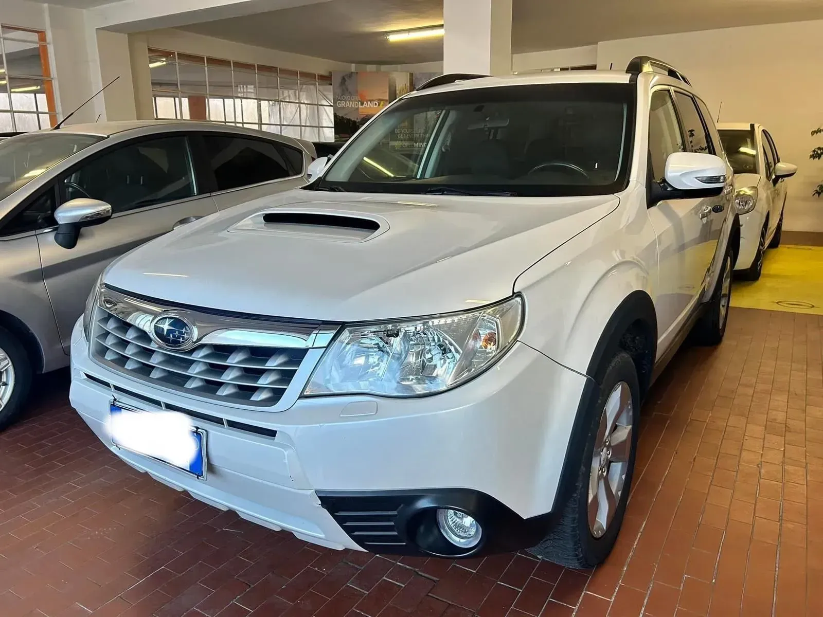 SUV bianco parcheggiato in un garage coperto accanto a un'altra auto