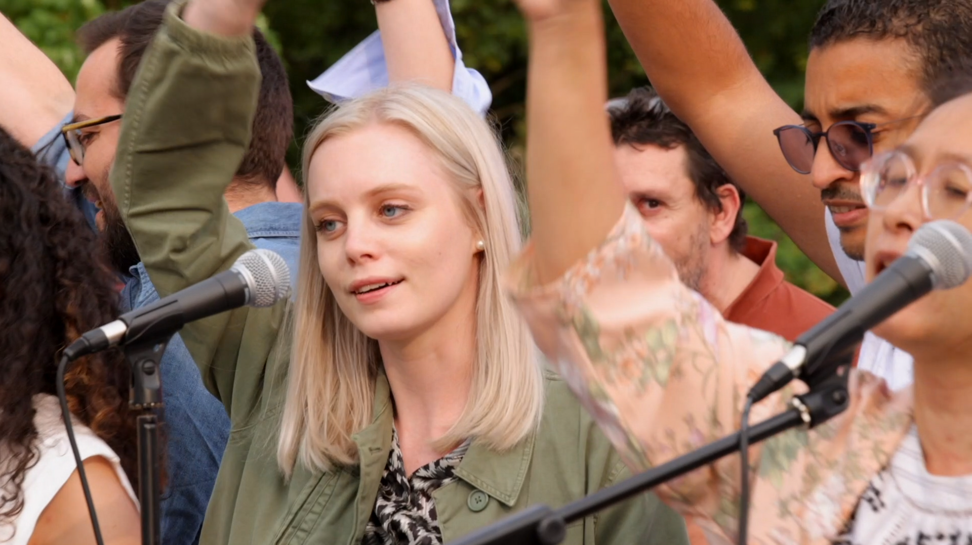Une femme chante dans un micro devant une foule de personnes.