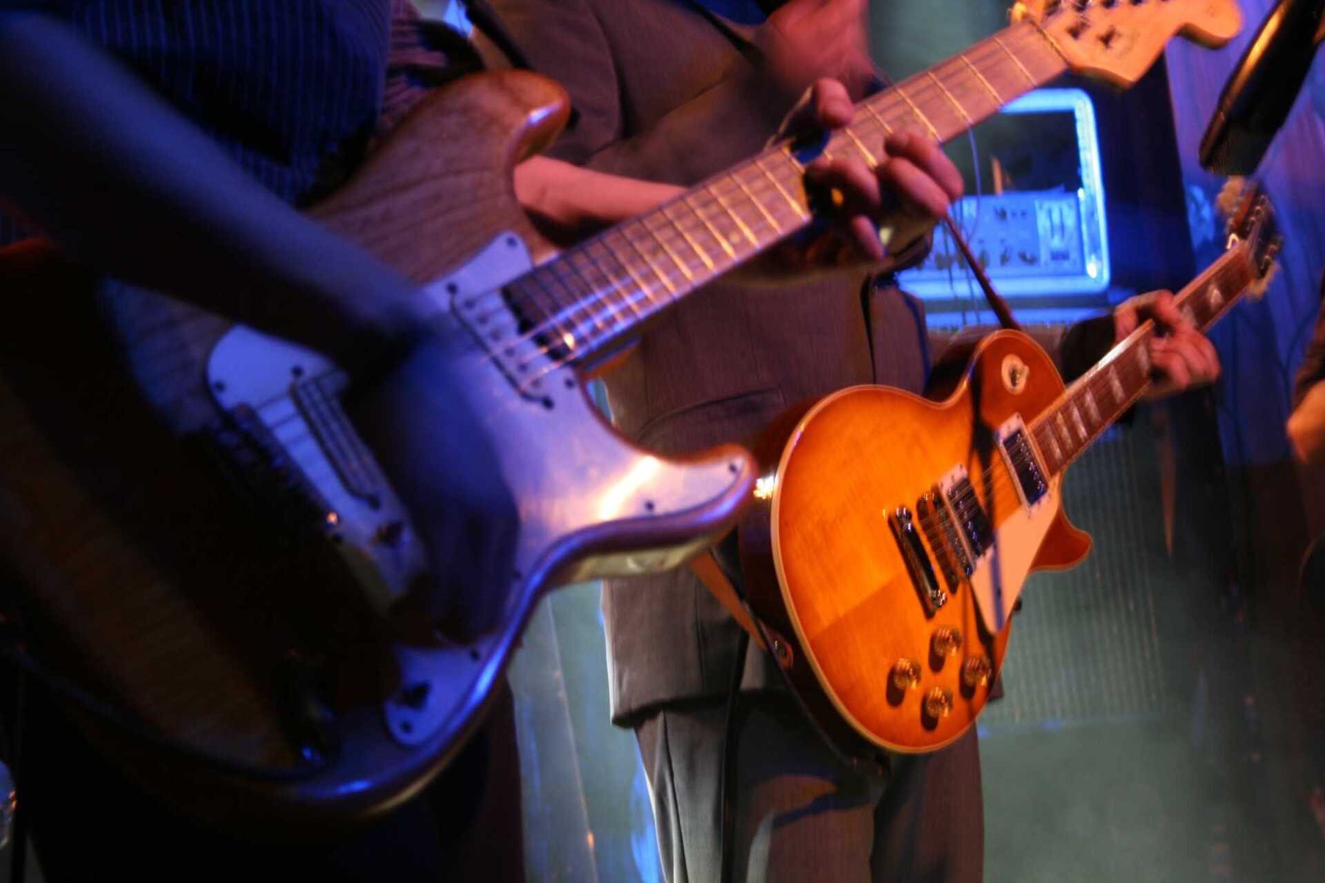 Un homme en costume joue de la guitare sur scène