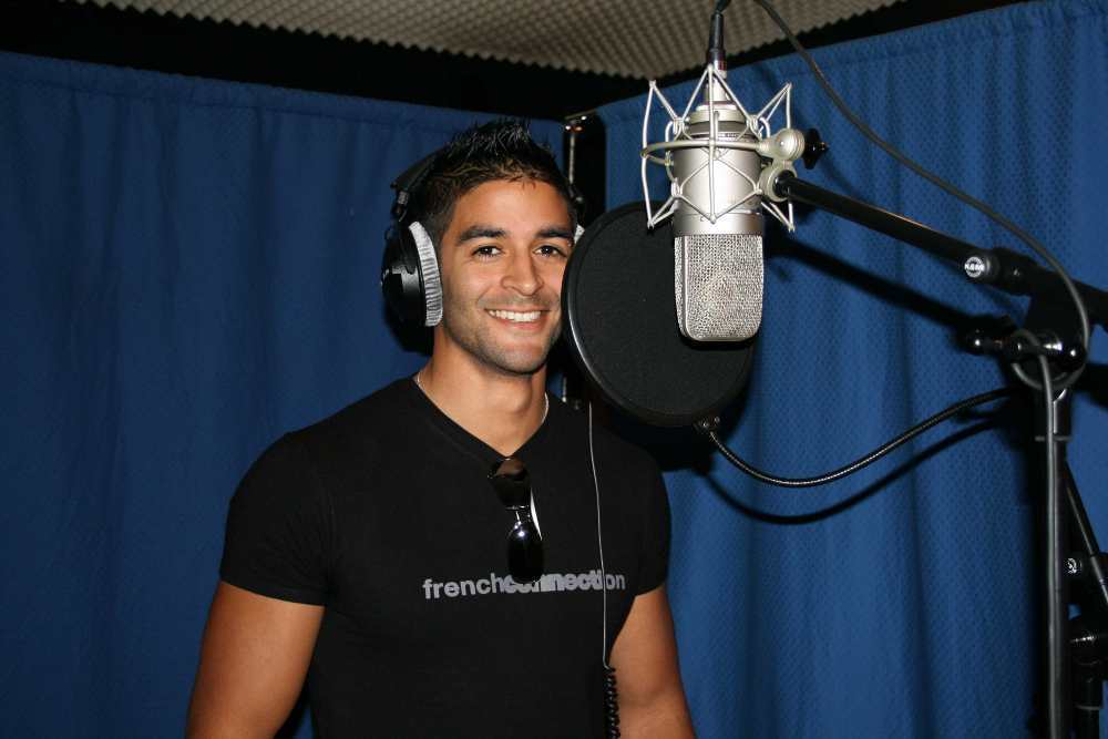 Un homme portant des écouteurs sourit devant un microphone