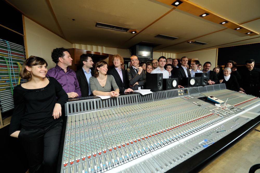 Un groupe de personnes se tient autour d'un grand mixeur dans une pièce.