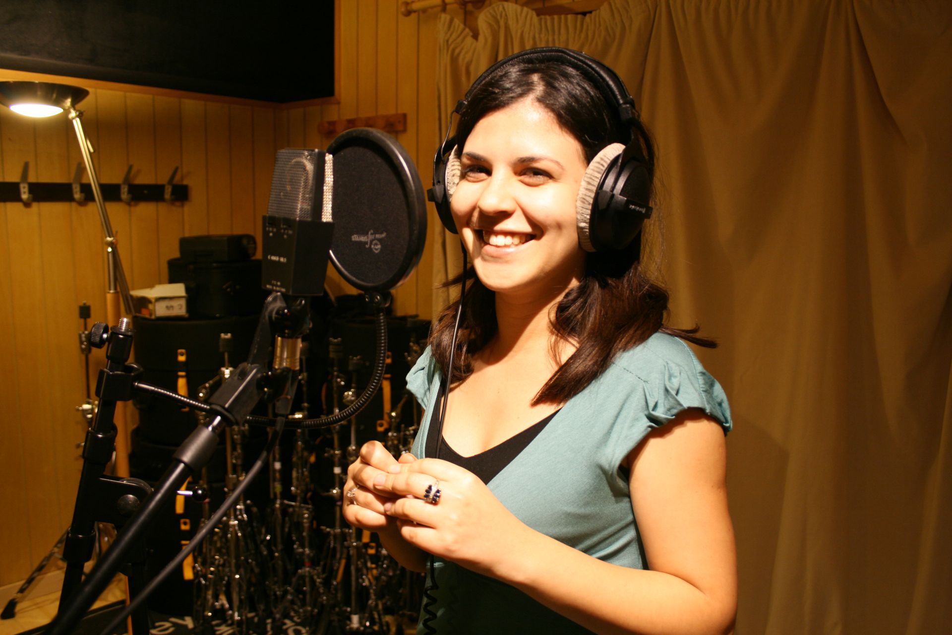 Une femme portant des écouteurs sourit devant un microphone
