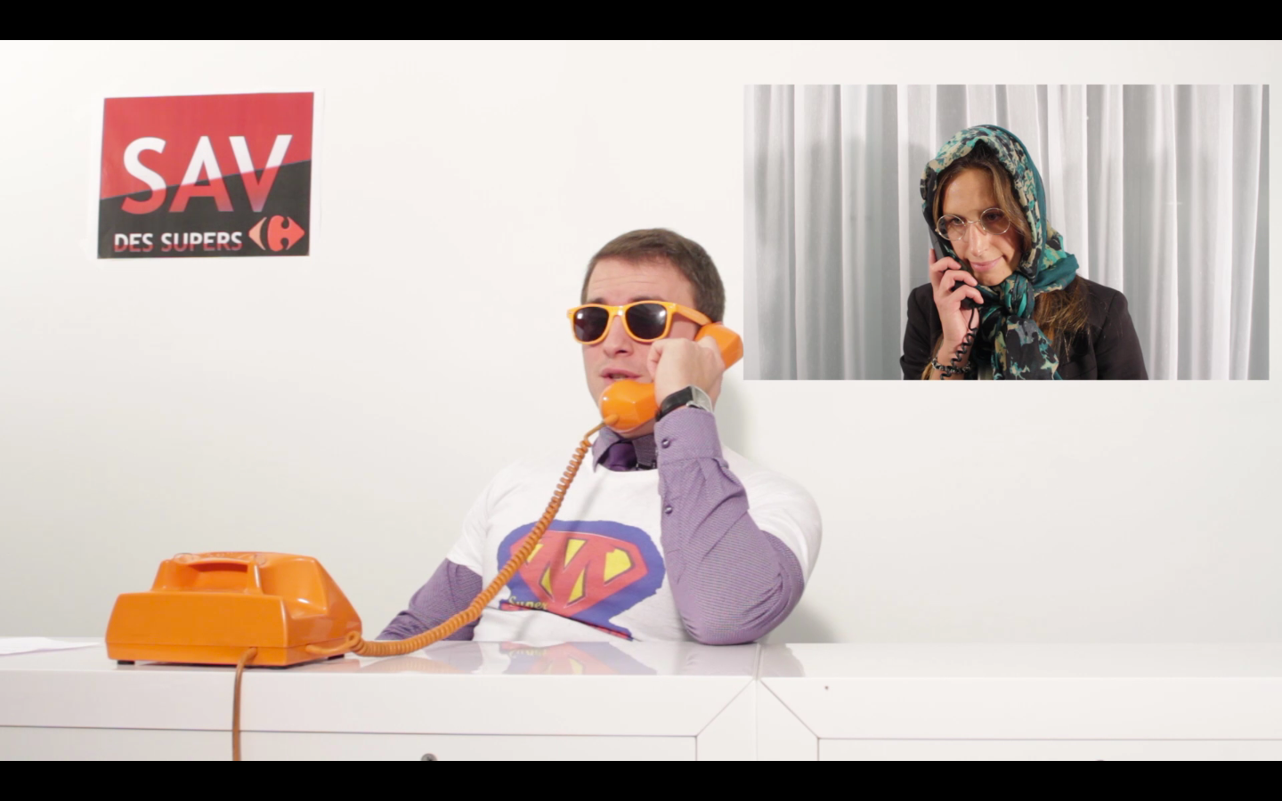 Un homme portant un t-shirt de Superman parle sur un téléphone orange