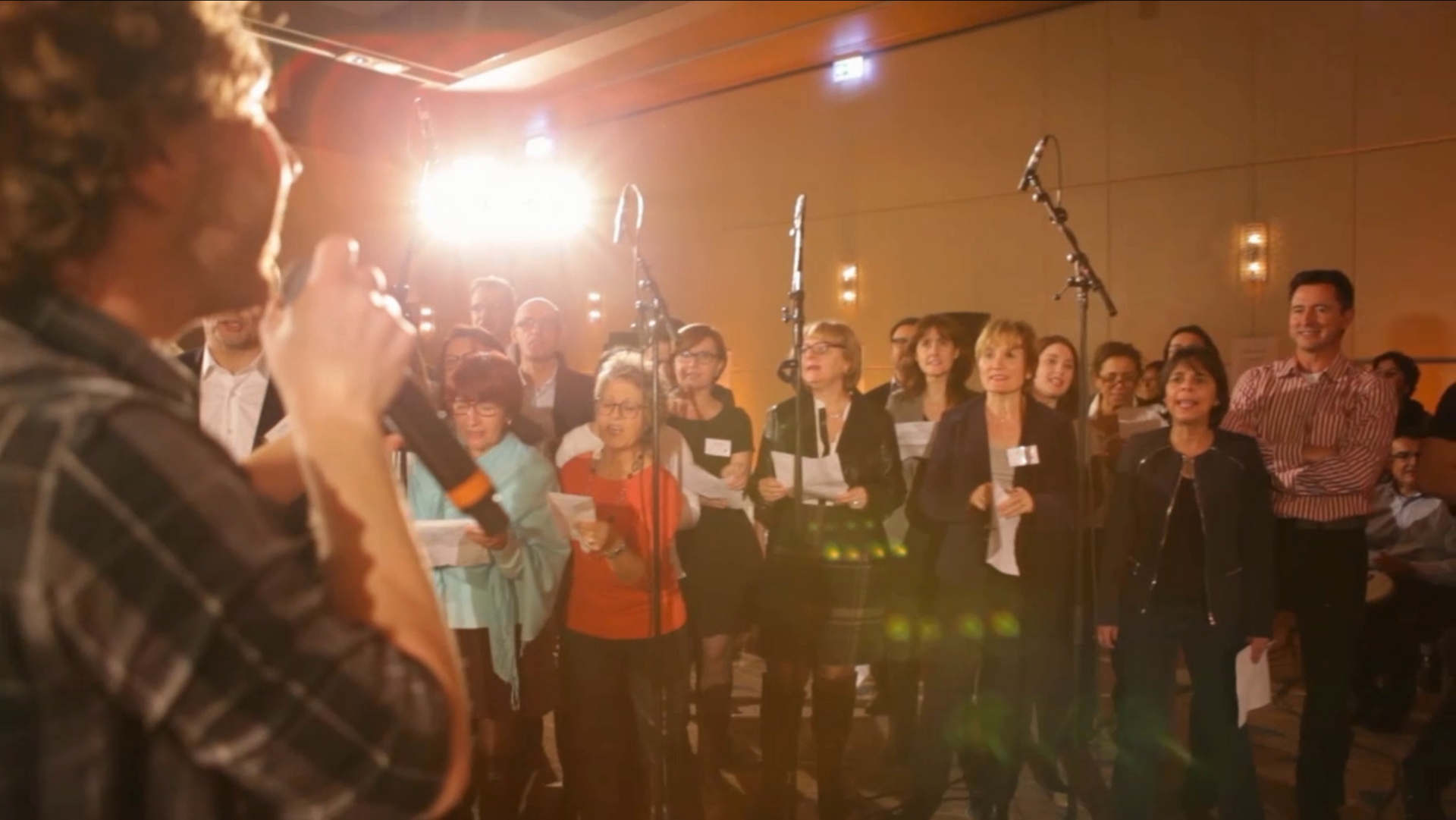 Un homme chante dans un micro devant une foule de personnes.