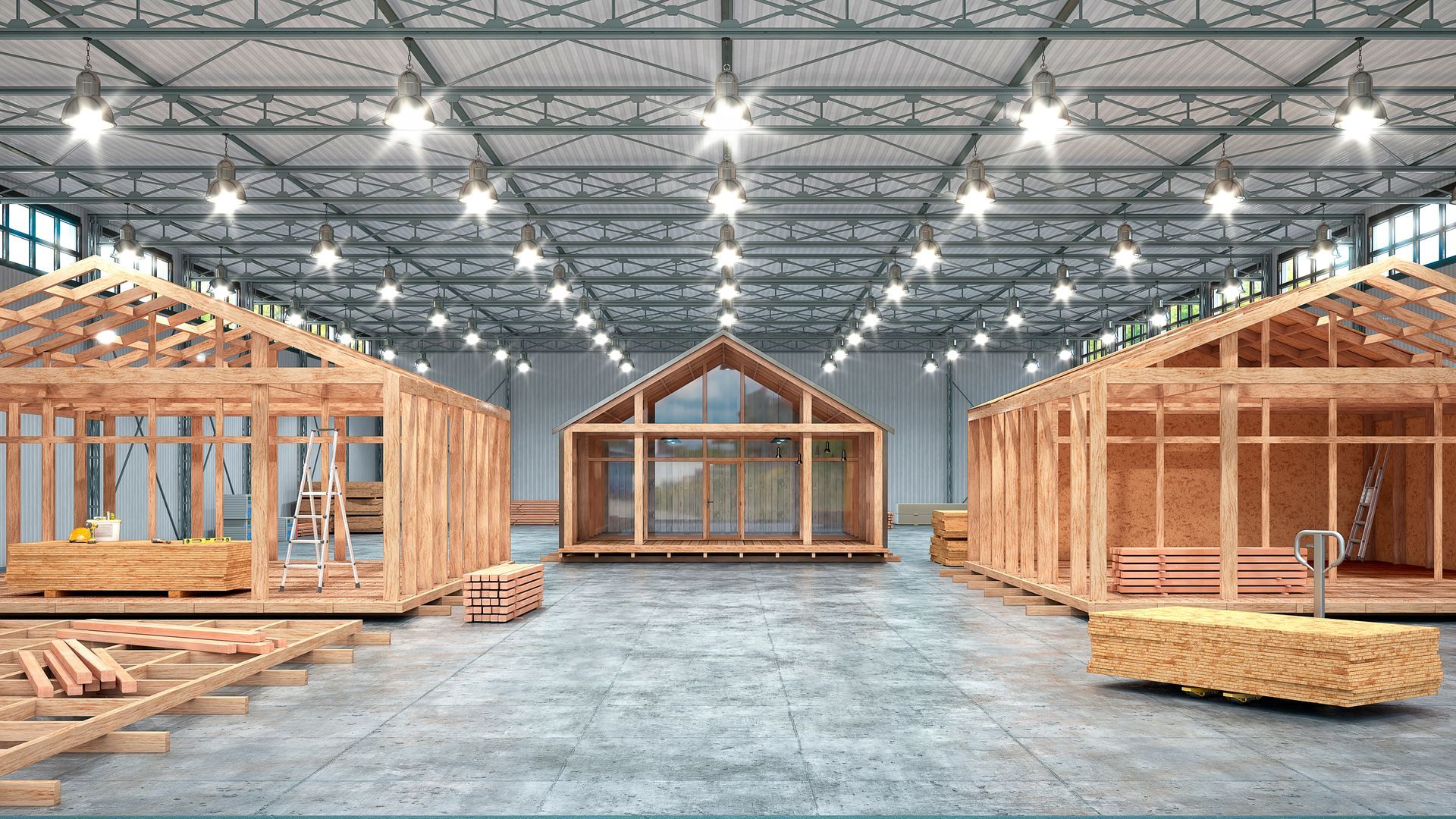 Spacious warehouse with three wooden house frames under construction and a metal truss ceiling