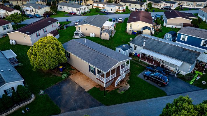 Aerial view of a suburban neighborhood with houses, driveways, and parked cars at dusk