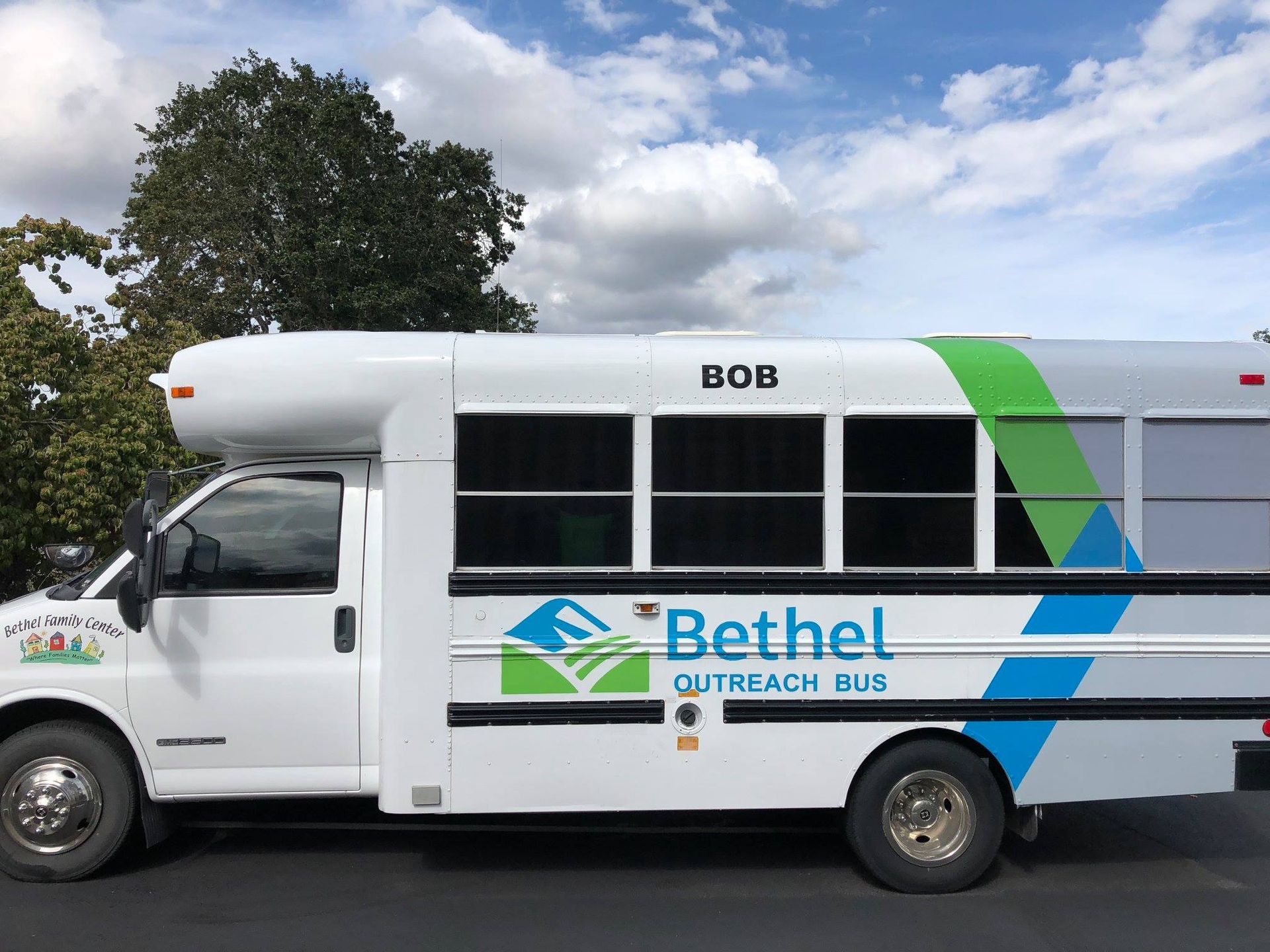 A white bus with the word bethel on the side is parked on the side of the road.