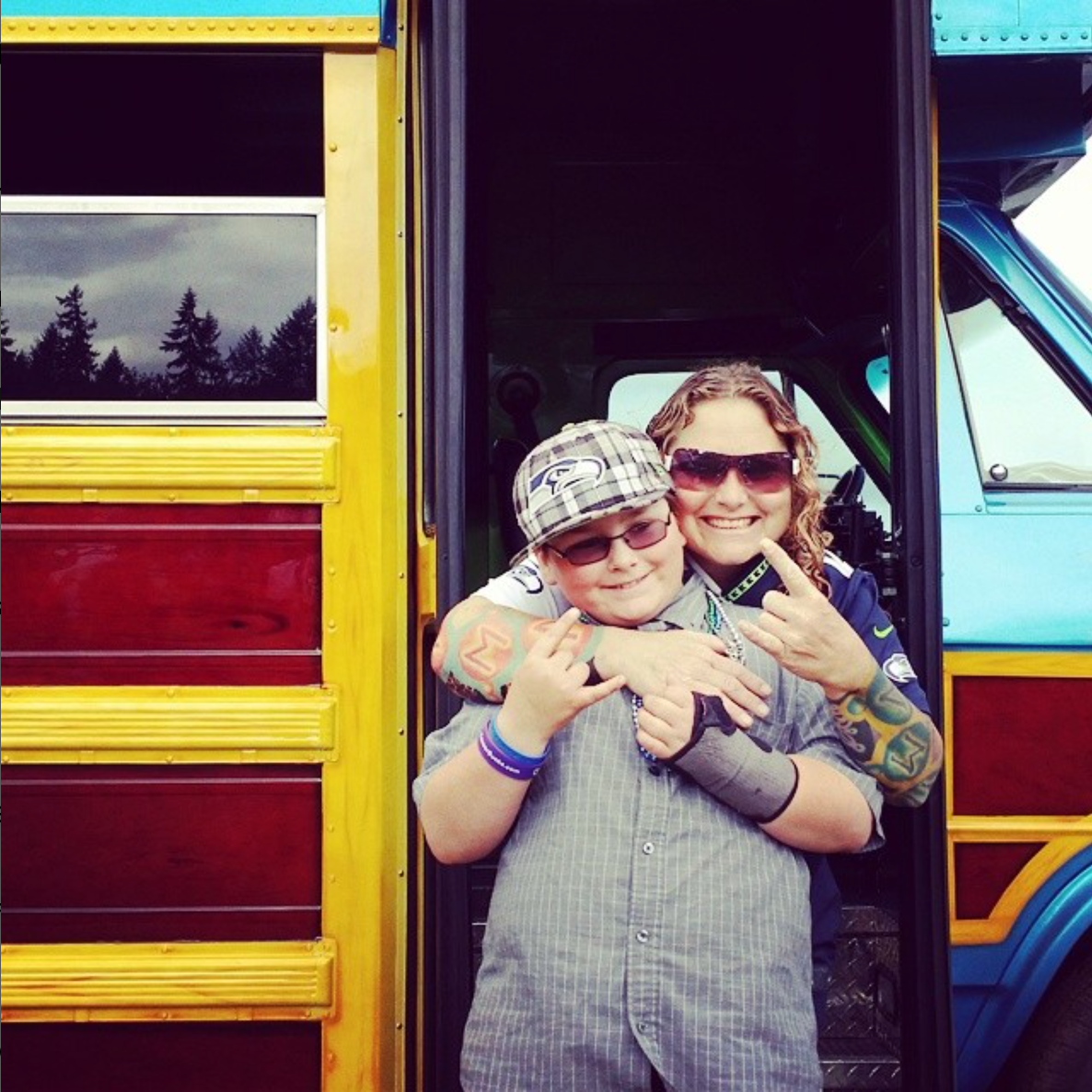 A woman and a boy are posing for a picture in front of a bus