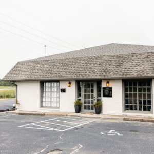 Small white storefront with large windows and parking spaces in front