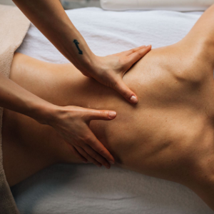 Hands giving a back massage on a person lying on a white sheet.