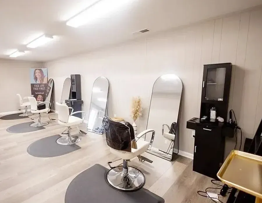 Bright salon with styling chairs, mirrors, and a red sofa along the left wall.