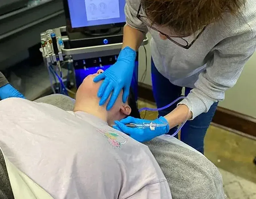 Medical worker in blue gloves examining a patient’s neck in a clinical setting