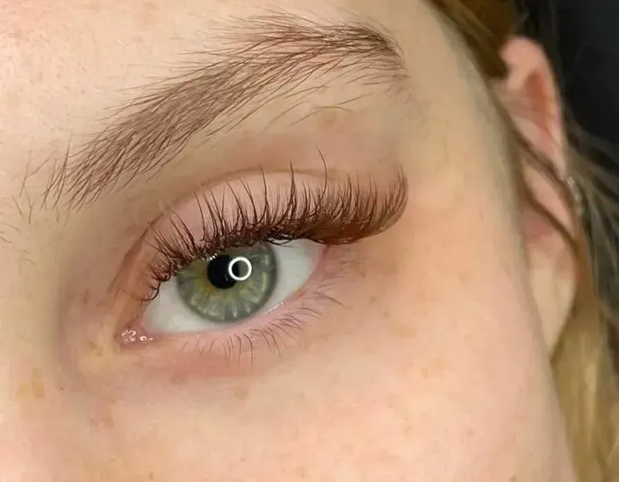 Close-up of a green eye with long curled lashes and natural brow makeup