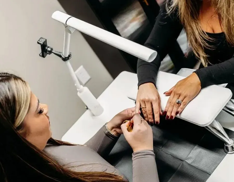 Manicurist painting a client's nails at a salon manicure station