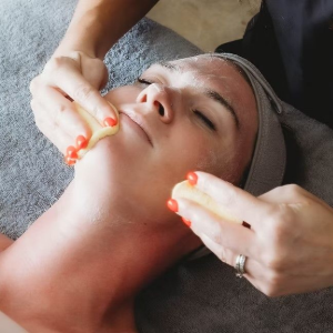 Spa facial massage with hands applying cream to a woman lying on a treatment table