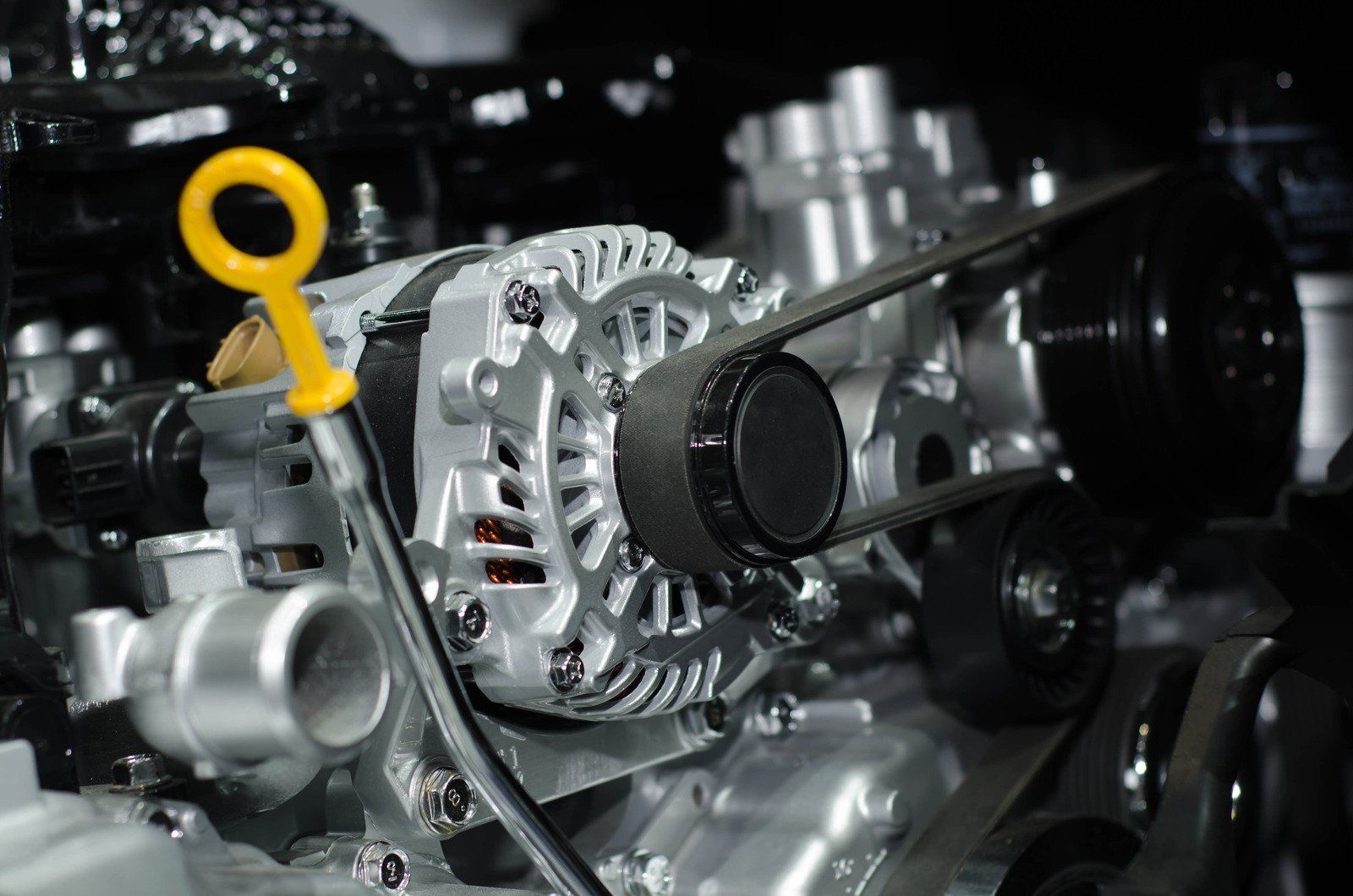 A close up of a car engine with an alternator and belt.